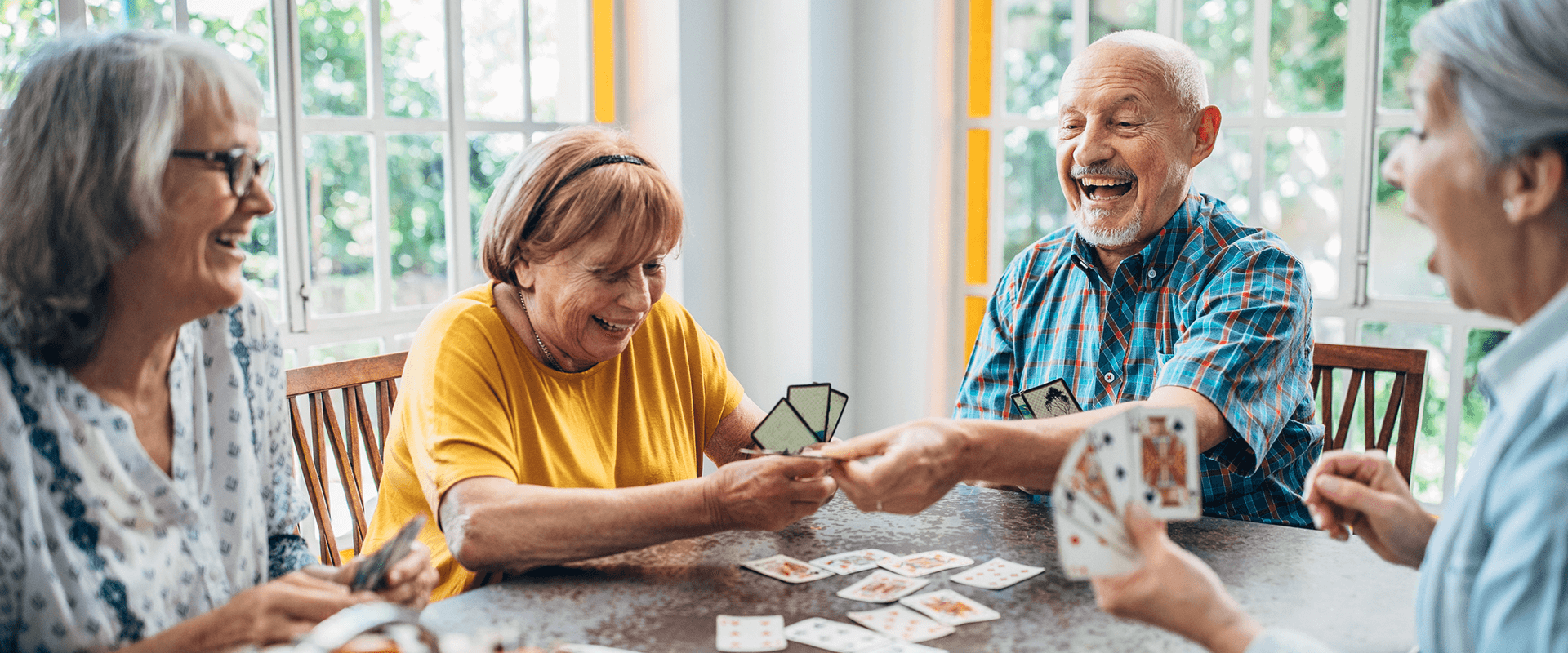 Senior friends sitting around a table playing cards