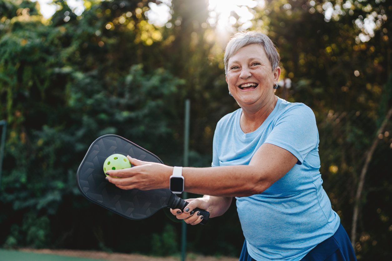 Portrait senior woman playing pickleball smiling