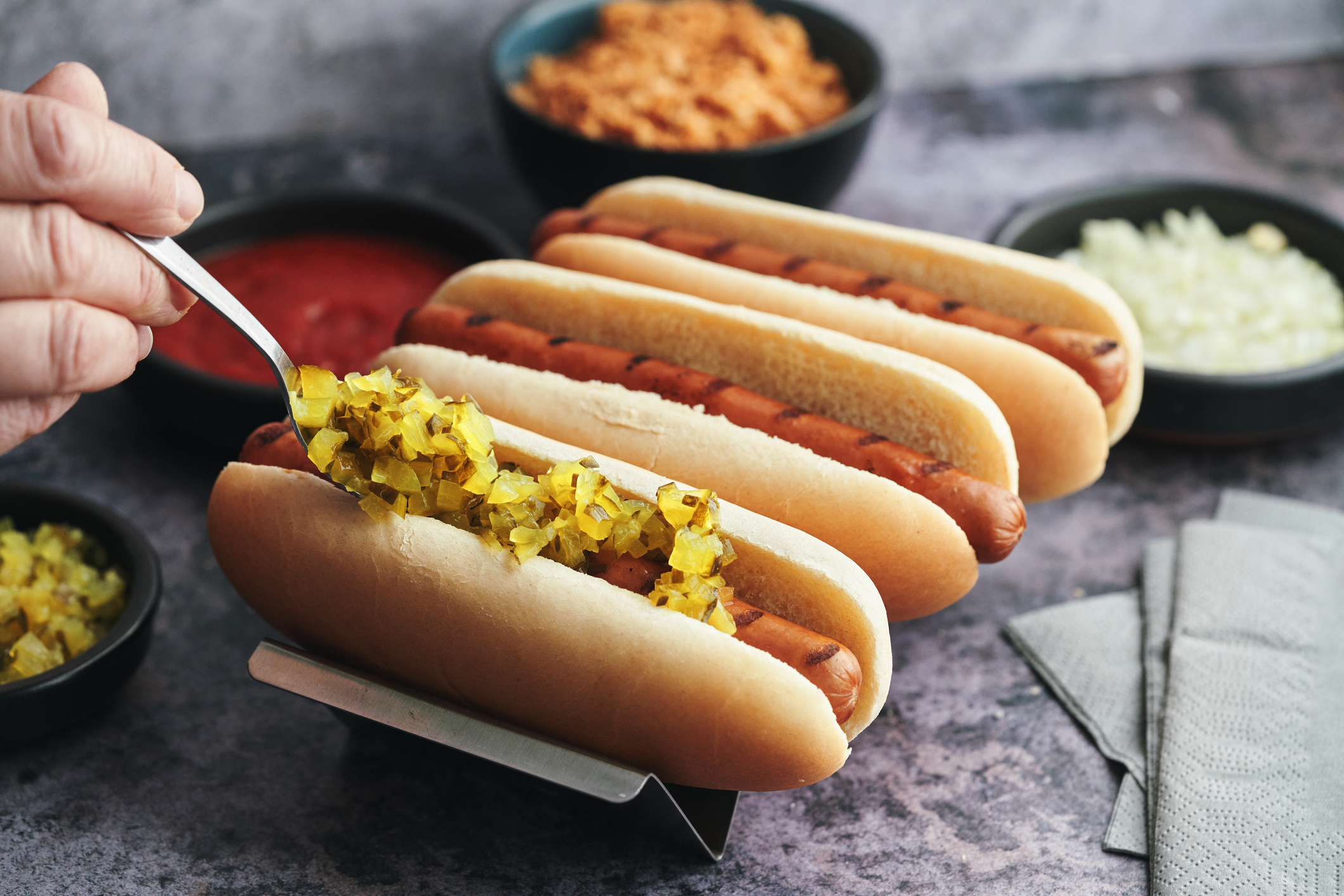 Variation of Hot Dogs with Roasted Onions, Pickle Relish, Mustard, Ketchup and Various Toppings
